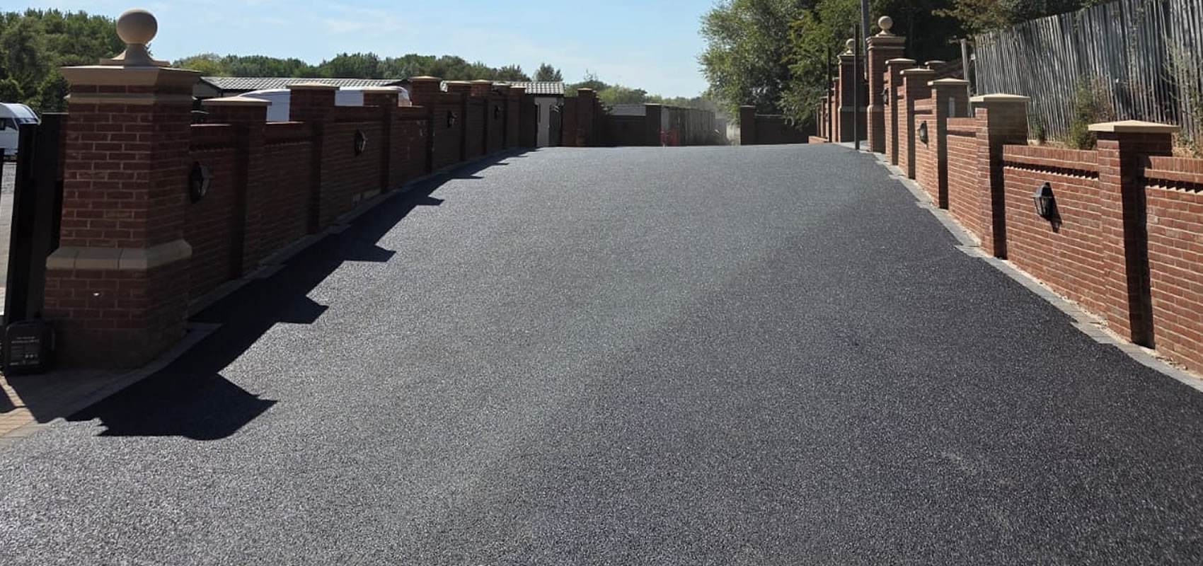 Finished tarmac driveway with brick boundary walls and entrance pillars